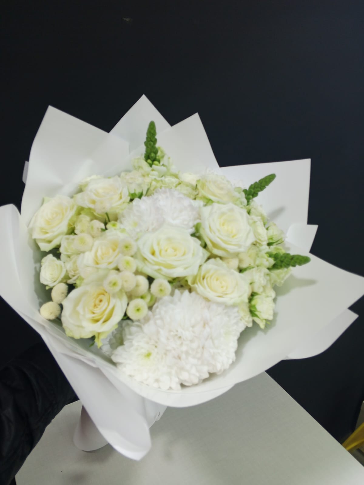 White roses, chrysanthemums and snapdragons in pristine white wrapper